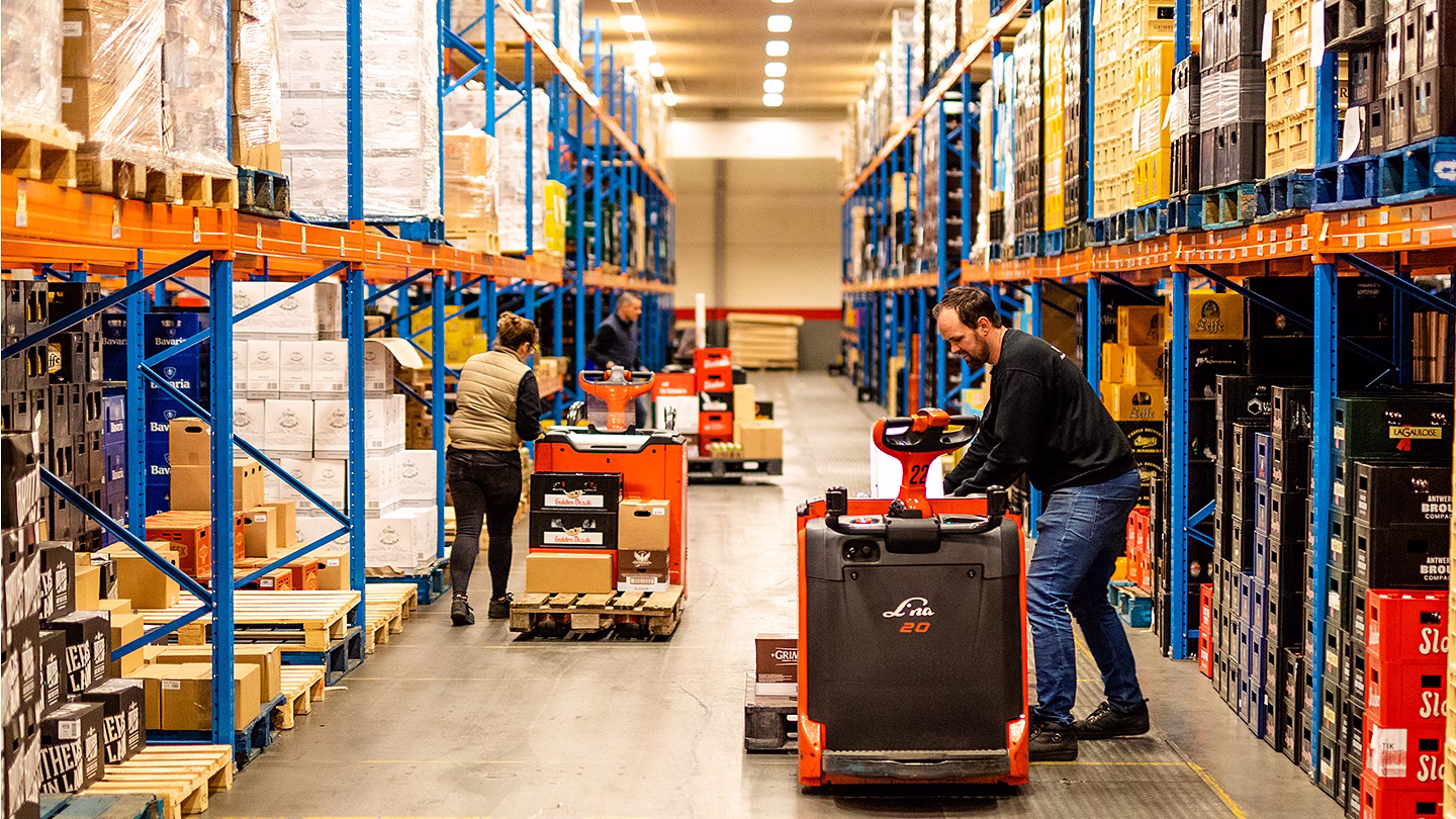 Magazijnmedewerker op een heftruck tussen hoge stellingen in een groot distributiecentrum