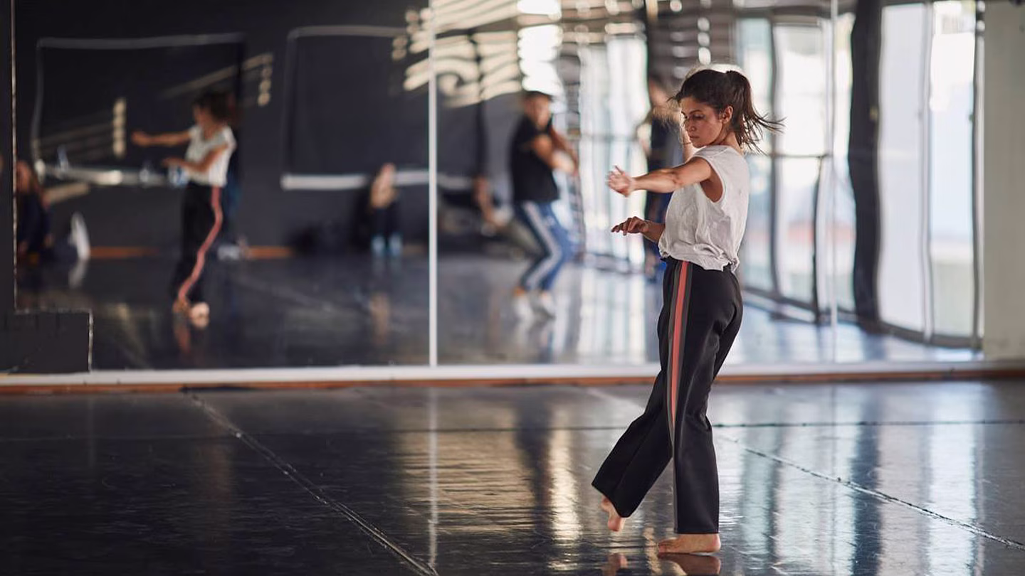 Balletdanseres oefent pirouette in dansstudio met spiegel op de achtergrond