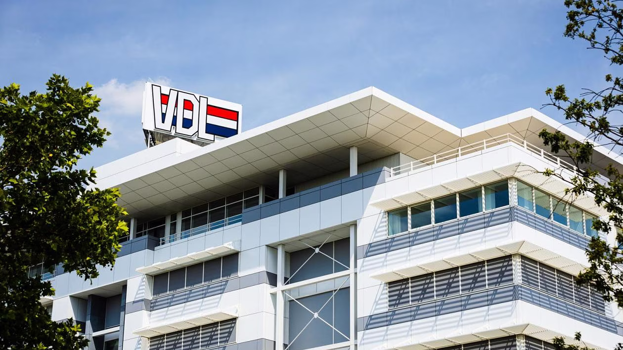 Modern wit kantoorgebouw met glazen gevels en bomen op voorgrond