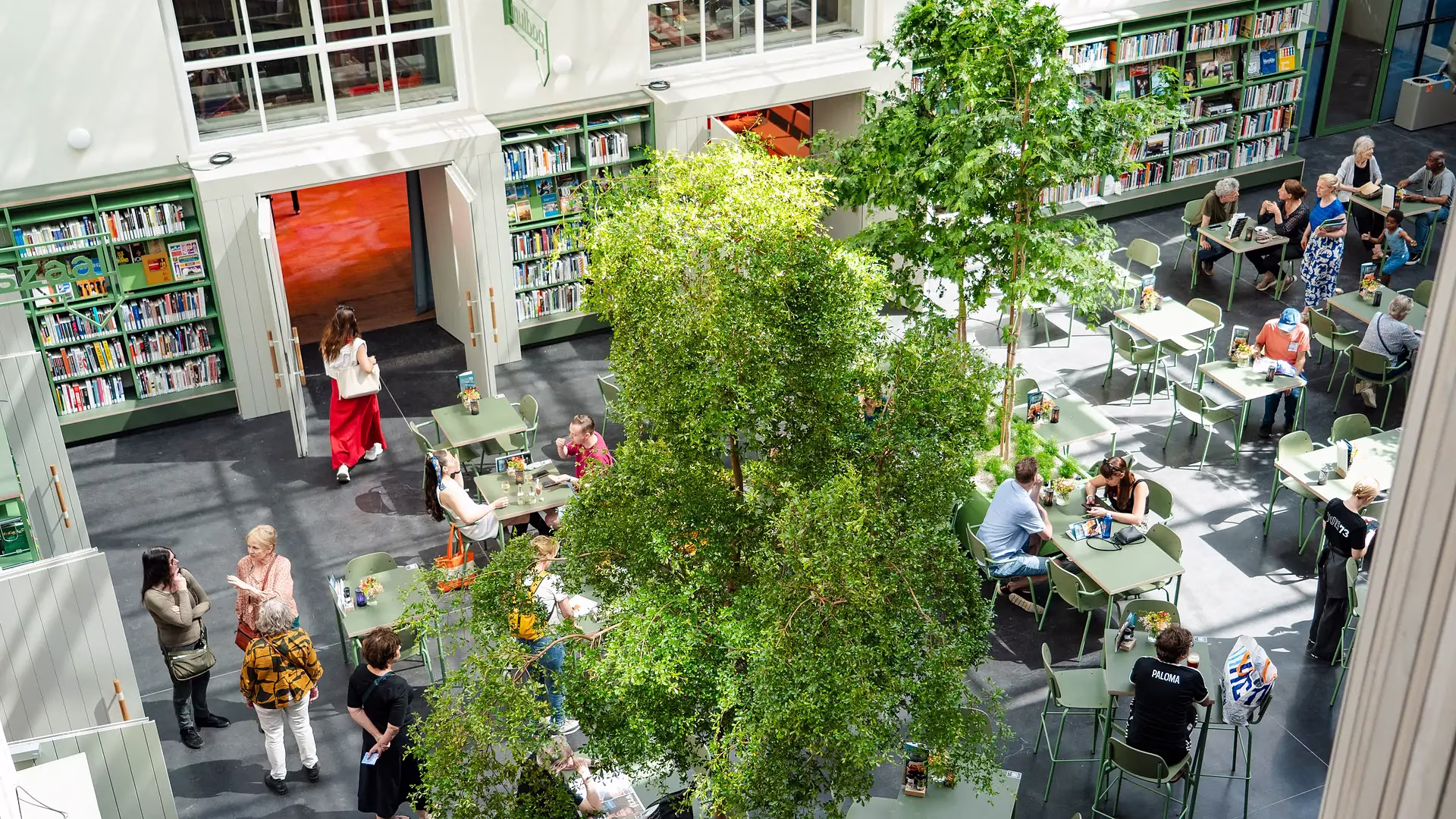 Binnenplaats met terras, grote boom en mensen aan tafels