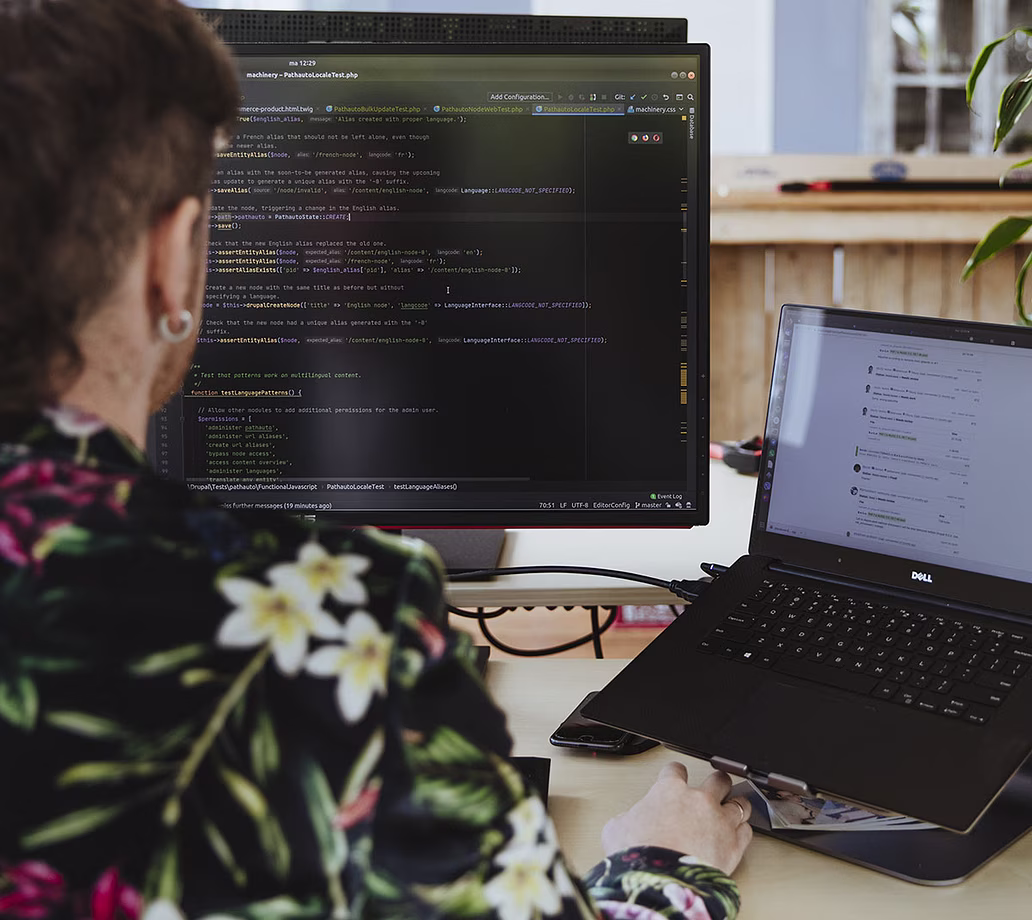 Persoon die op laptop werkt met code op extern scherm