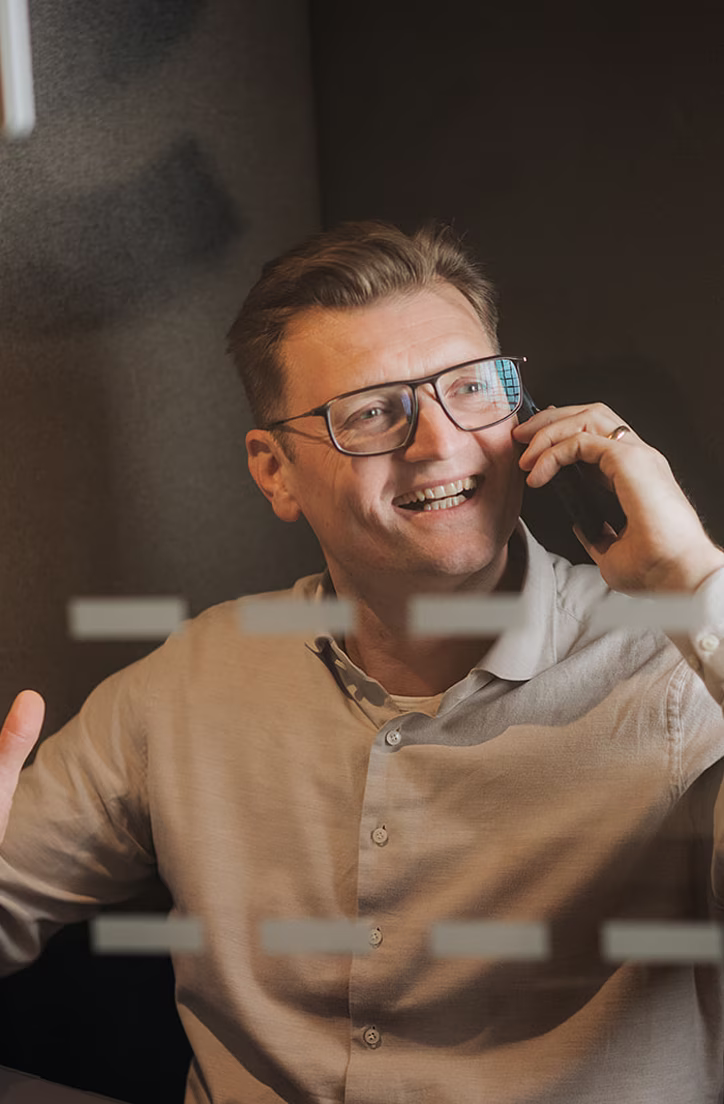 Oudere man met bril belt met telefoon terwijl hij koffie drinkt