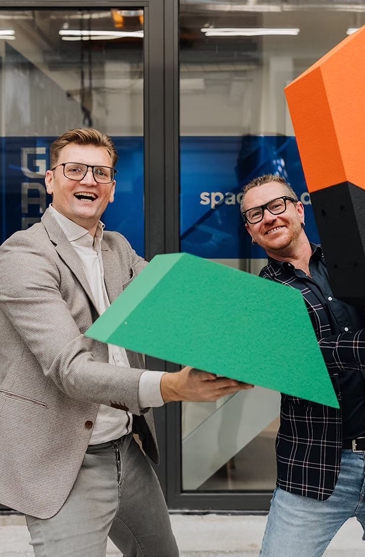 Drie mannen poseren met gekleurde vormen voor een verweerde blauwe deur