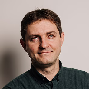 Man in donkergroen shirt met gekruiste armen voor lichte achtergrond